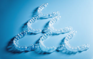 Invisalign lined up in a pyramid shape on a blue background