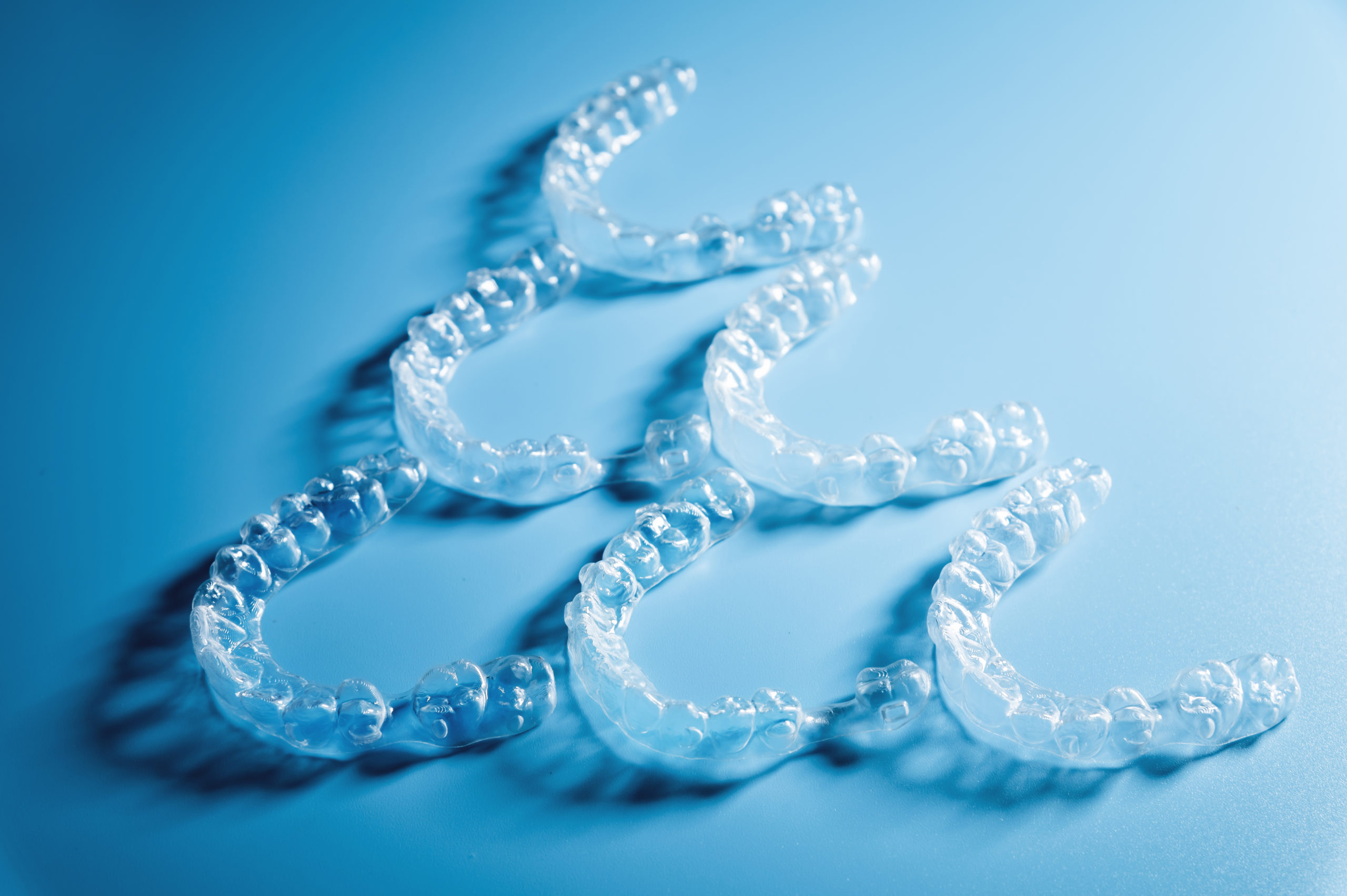 Invisalign lined up in a pyramid shape on a blue background