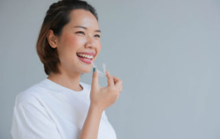 close up of a young asian woman smiling with Invisalign in her hand