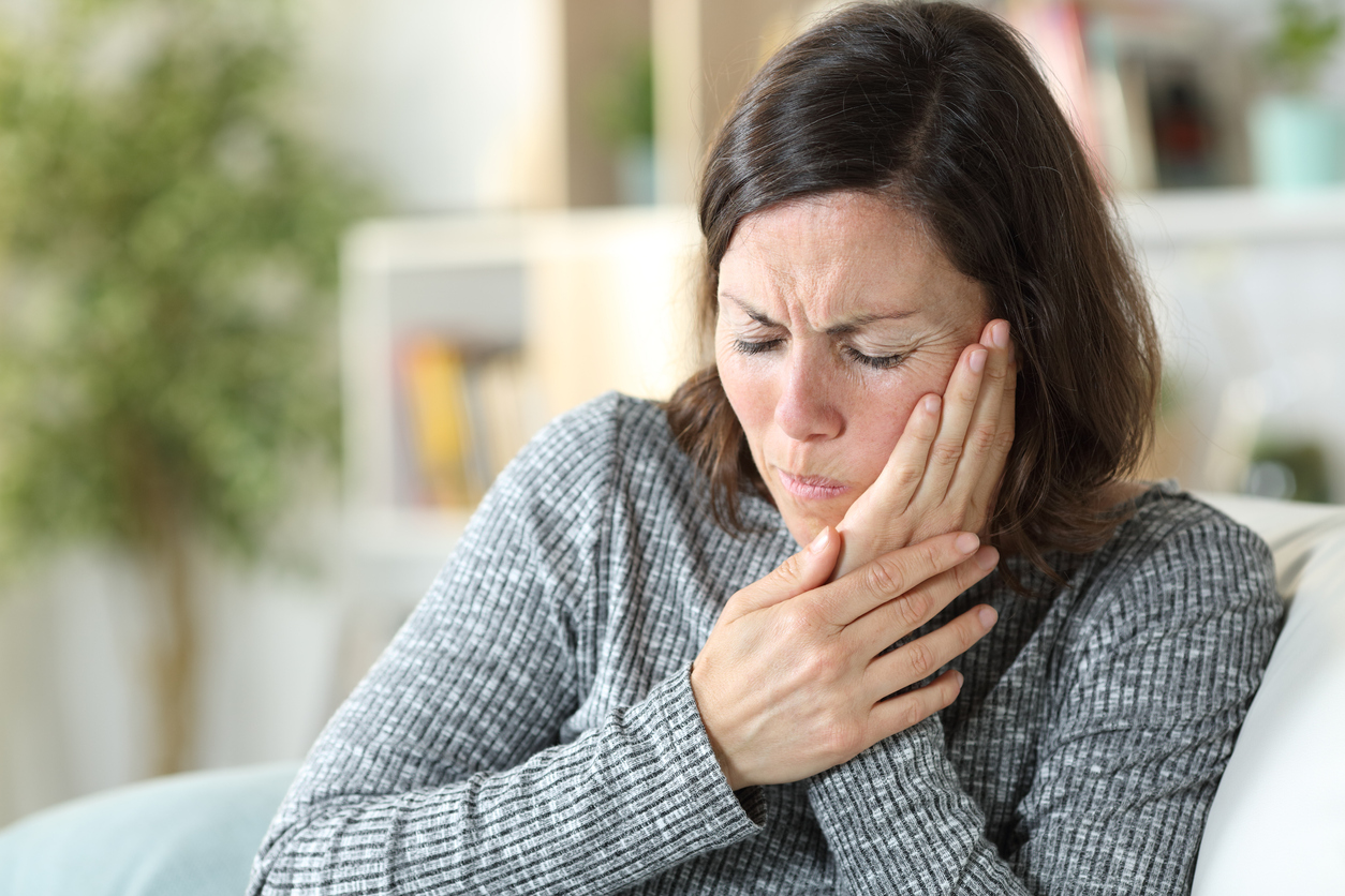 Middle age woman suffering from jaw pain at home