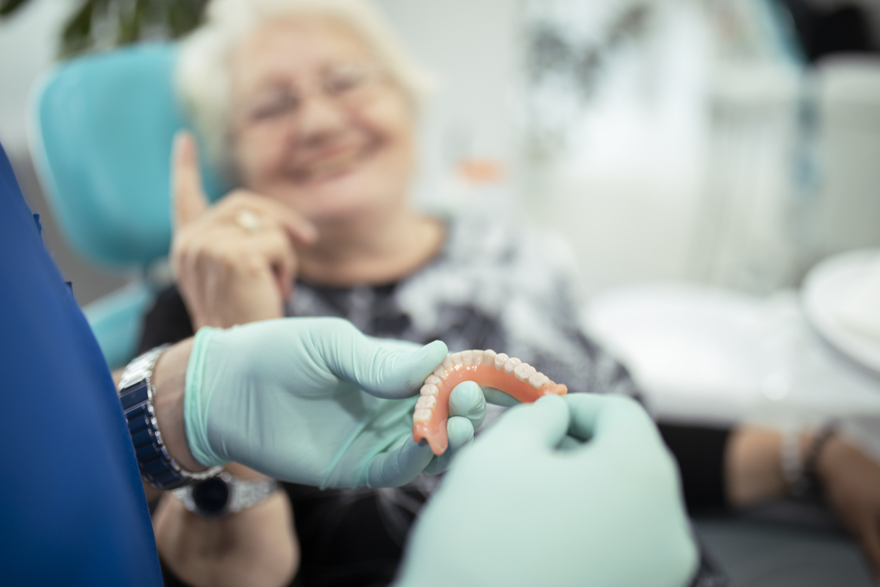 dentist showing dentures to patient