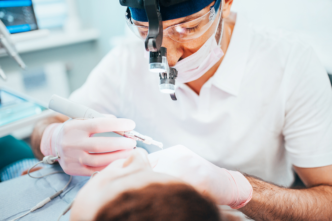 Dentist cleans tooth canals of patient and re - root canal treatment